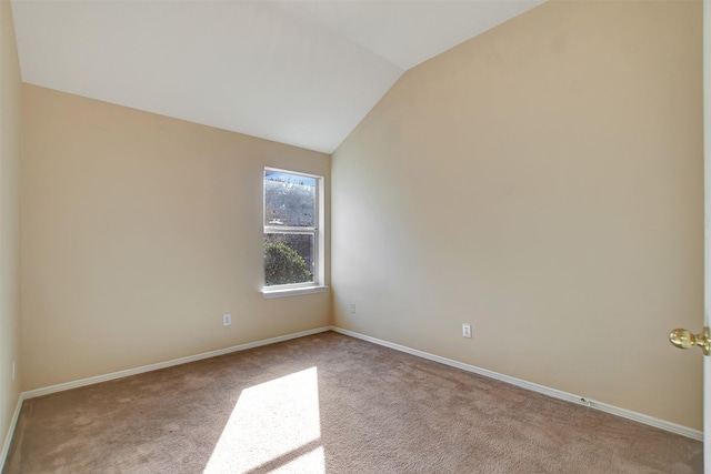 empty room featuring vaulted ceiling, light carpet, and baseboards