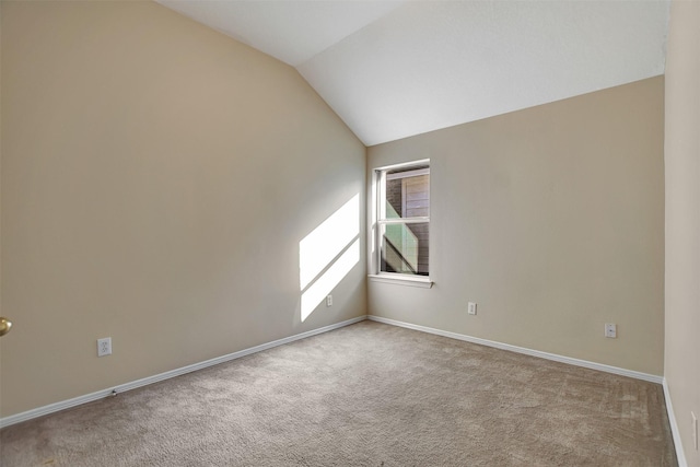 empty room with lofted ceiling, light carpet, and baseboards