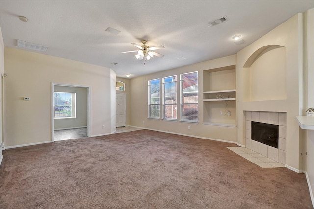 unfurnished living room with built in shelves, a fireplace, light colored carpet, visible vents, and a textured ceiling