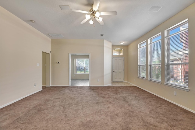 unfurnished living room featuring light colored carpet, ceiling fan, visible vents, and baseboards