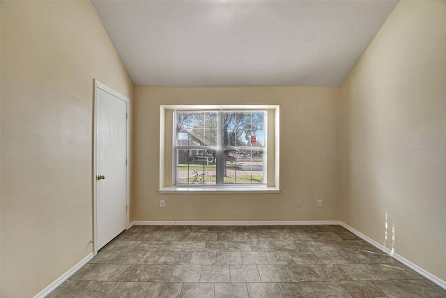 unfurnished room with vaulted ceiling and baseboards