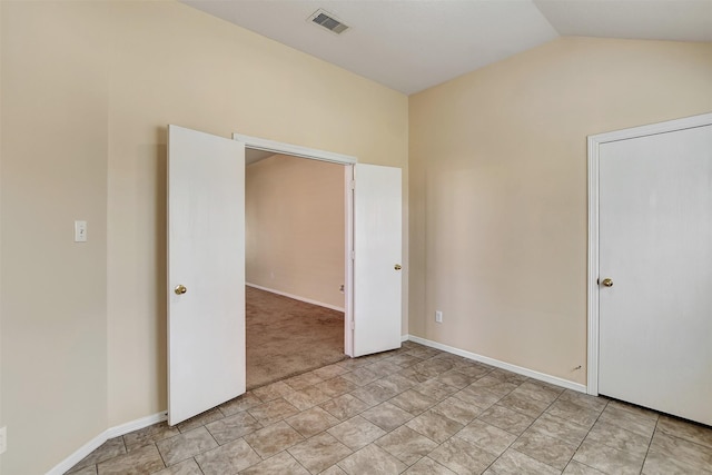 unfurnished bedroom with lofted ceiling, visible vents, and baseboards