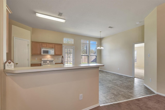 kitchen with a peninsula, white appliances, visible vents, and light countertops