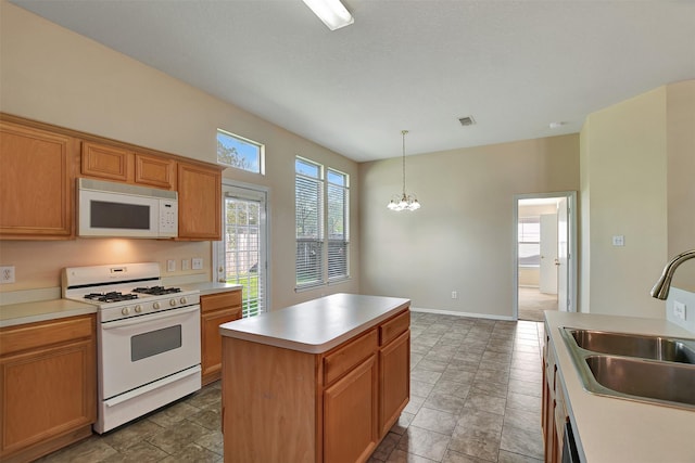 kitchen featuring a center island, decorative light fixtures, light countertops, a sink, and white appliances