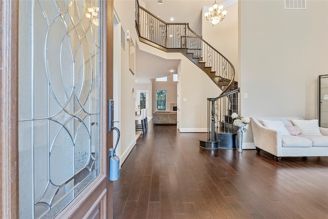 entryway with dark wood-style floors, visible vents, a towering ceiling, an inviting chandelier, and stairs