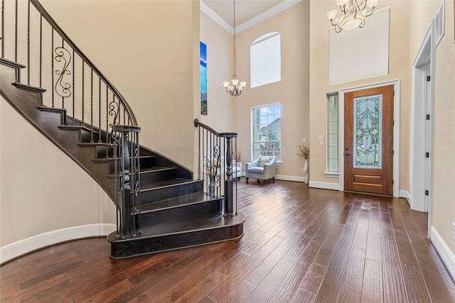 foyer with baseboards, ornamental molding, wood finished floors, an inviting chandelier, and stairs