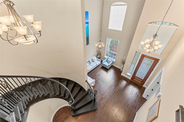 entryway featuring dark wood finished floors, a notable chandelier, a high ceiling, baseboards, and stairs