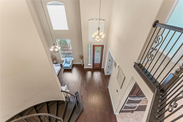 entryway featuring stairs, wood finished floors, a towering ceiling, and an inviting chandelier