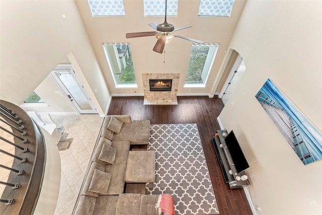 living area featuring a tile fireplace, a healthy amount of sunlight, dark wood finished floors, and a high ceiling