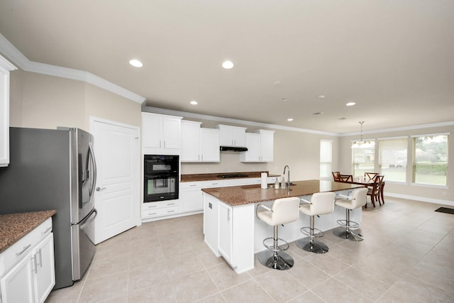 kitchen with dark stone counters, stainless steel fridge with ice dispenser, an island with sink, a breakfast bar area, and under cabinet range hood