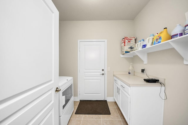 clothes washing area with light tile patterned floors, independent washer and dryer, cabinet space, and baseboards