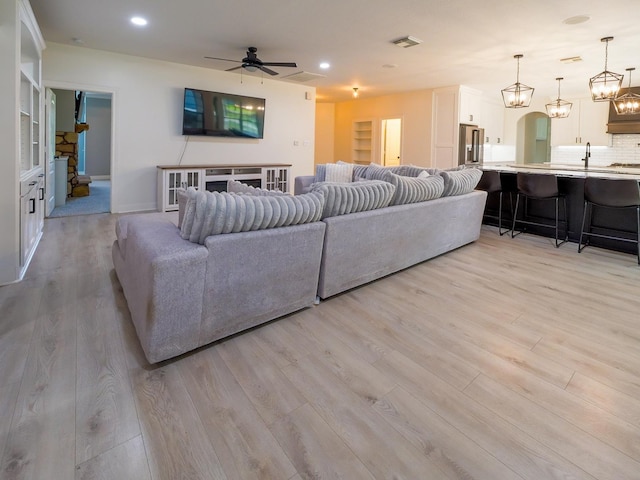 living area with visible vents, arched walkways, a ceiling fan, light wood-style flooring, and recessed lighting