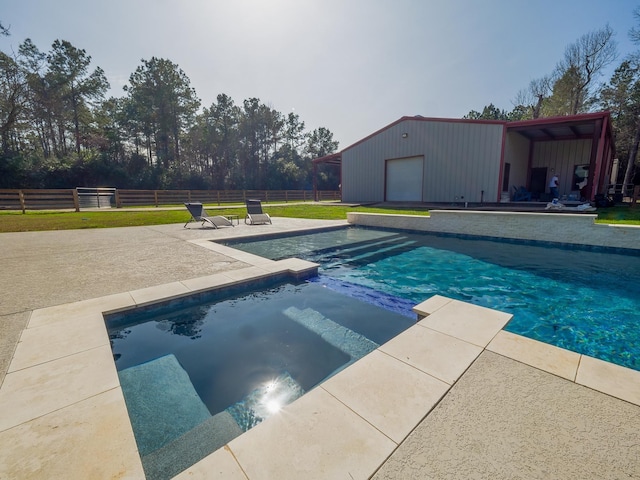 view of swimming pool featuring a patio area, a pool with connected hot tub, fence, and an outdoor structure