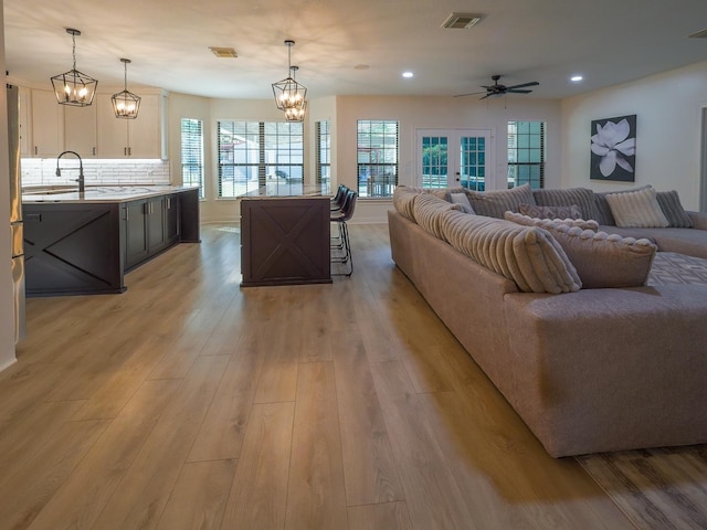 living area featuring light wood-style floors, recessed lighting, visible vents, and ceiling fan with notable chandelier