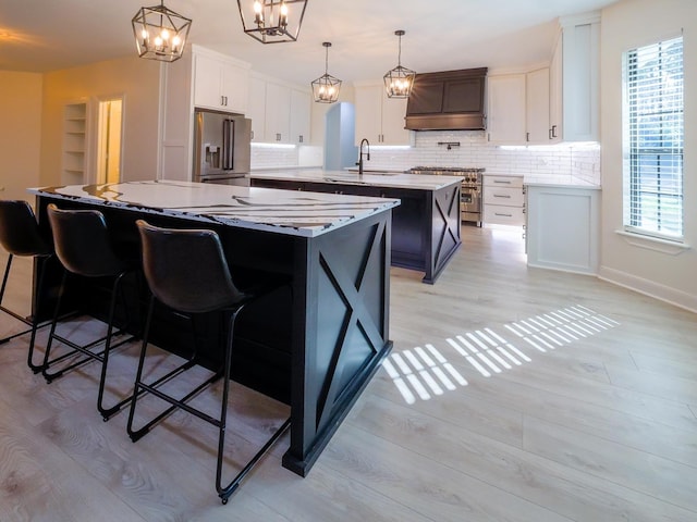 kitchen featuring light wood finished floors, a spacious island, high quality appliances, a chandelier, and backsplash