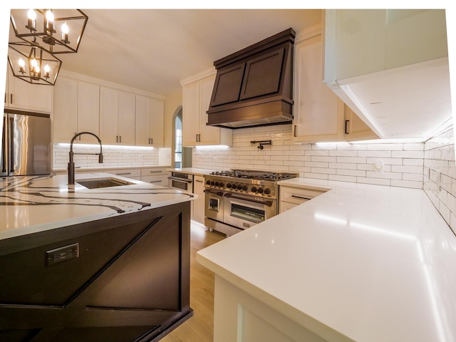 kitchen with appliances with stainless steel finishes, arched walkways, premium range hood, and backsplash