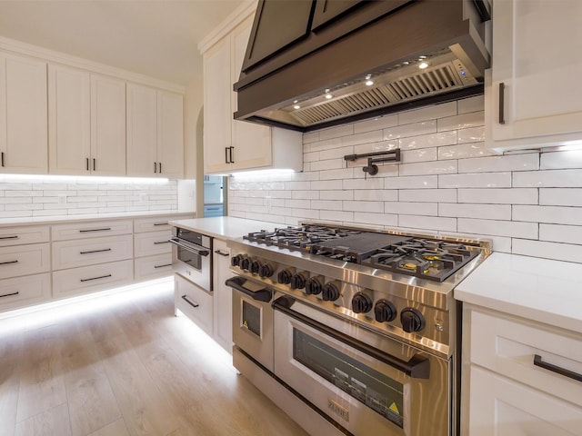 kitchen featuring light countertops, custom exhaust hood, white cabinets, and double oven range