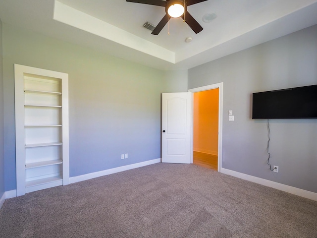 unfurnished bedroom with a tray ceiling, baseboards, visible vents, and carpet