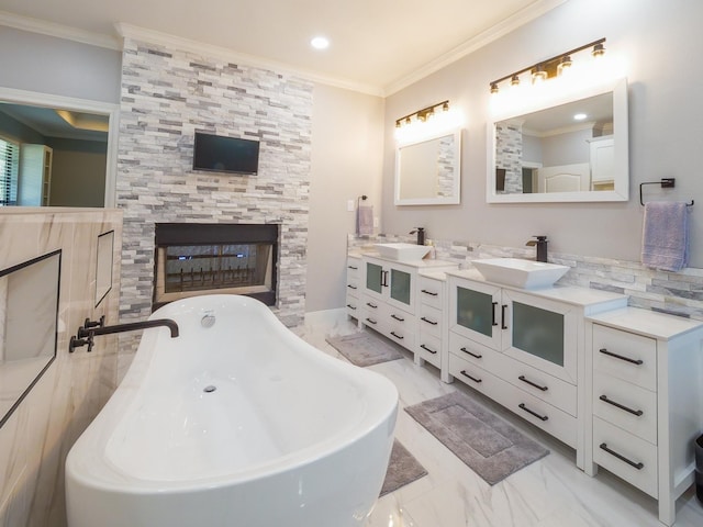 full bathroom featuring marble finish floor, ornamental molding, a soaking tub, and a sink