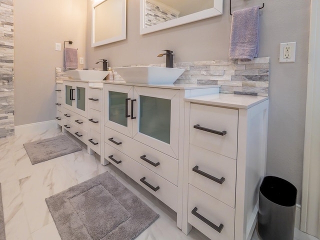 full bath featuring double vanity, marble finish floor, baseboards, and a sink