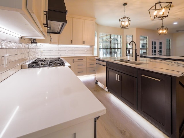 kitchen featuring a center island with sink, decorative backsplash, appliances with stainless steel finishes, extractor fan, and a sink