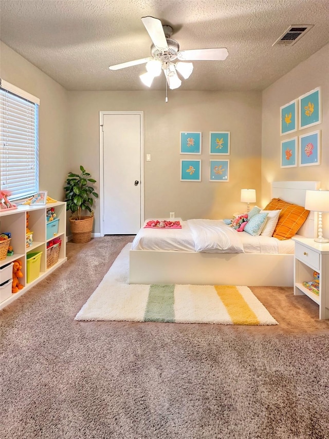 bedroom featuring carpet, visible vents, ceiling fan, and a textured ceiling