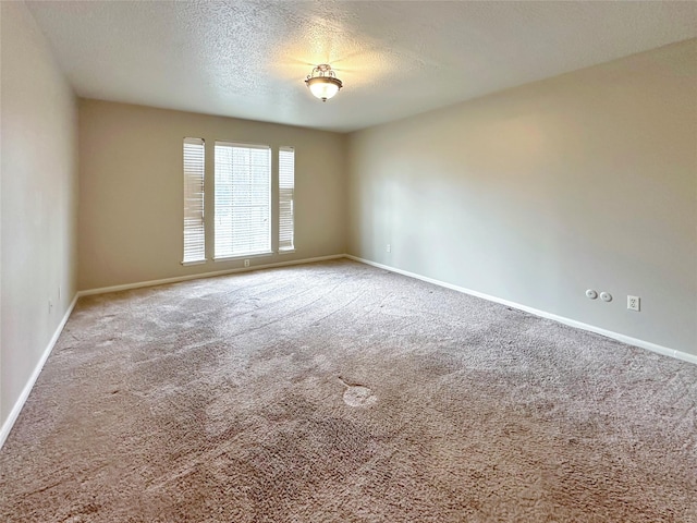 empty room featuring carpet, a textured ceiling, and baseboards