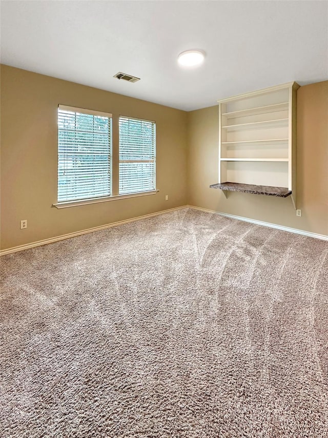 spare room featuring carpet flooring, visible vents, and baseboards