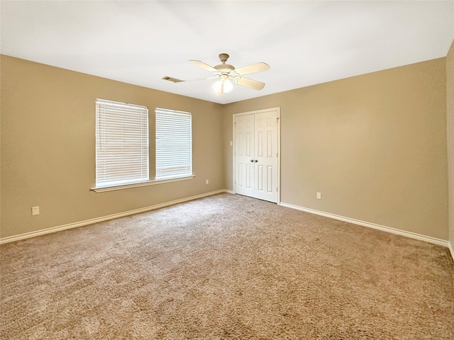 carpeted empty room featuring ceiling fan, visible vents, and baseboards