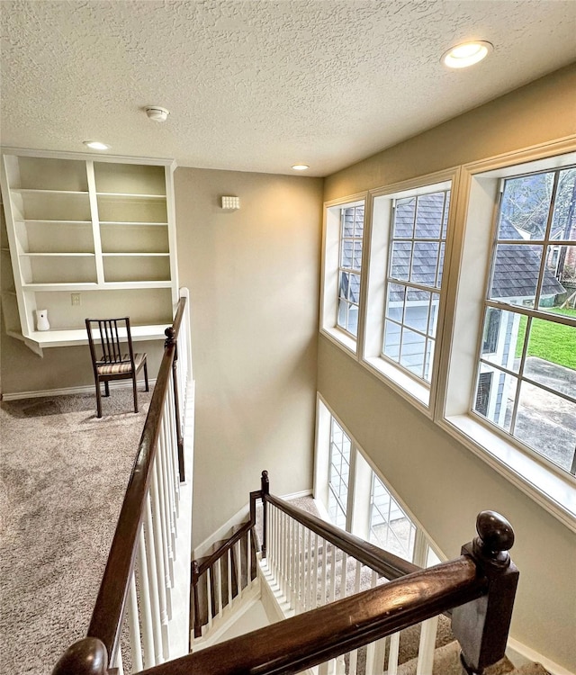 stairway with baseboards, a textured ceiling, carpet flooring, and recessed lighting