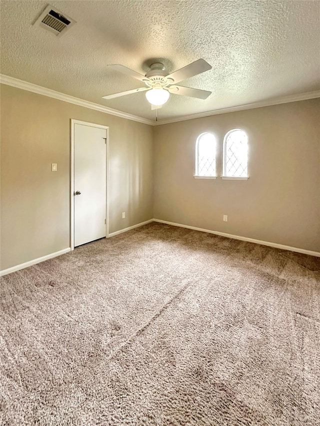 carpeted empty room featuring baseboards, visible vents, ornamental molding, and a ceiling fan