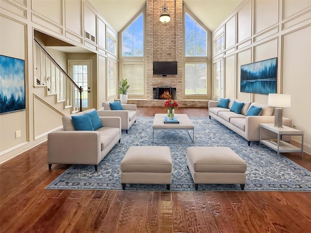 17439 Fairway Oaks Dr, Spring, TX 77379 - living room featuring wood finished floors, high vaulted ceiling, stairs, and a fireplace