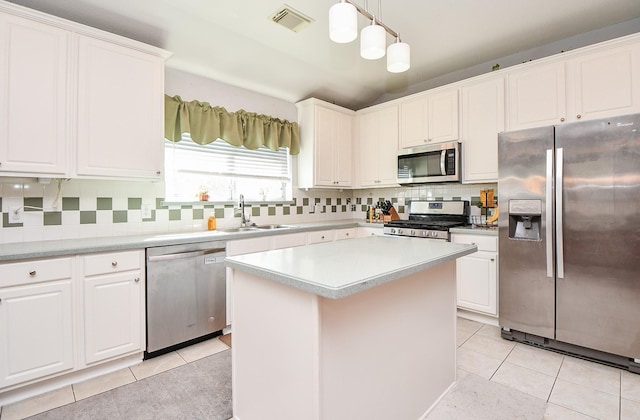 kitchen with a sink, light countertops, appliances with stainless steel finishes, a center island, and decorative light fixtures