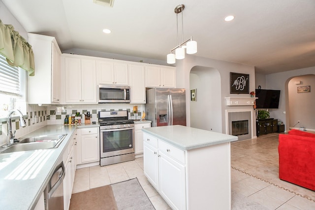 kitchen featuring a center island, stainless steel appliances, light countertops, white cabinets, and a sink