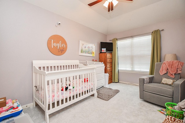 bedroom with lofted ceiling, a crib, carpet flooring, and baseboards