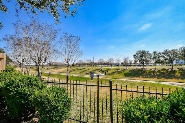 view of community featuring a rural view, fence, and a lawn