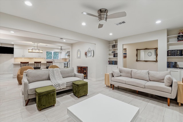 living area featuring visible vents, baseboards, ceiling fan, built in shelves, and recessed lighting