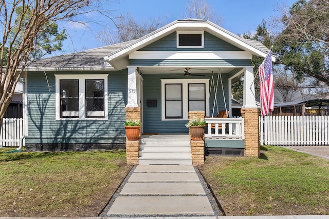 view of front facade with a ceiling fan, covered porch, fence, and a front lawn