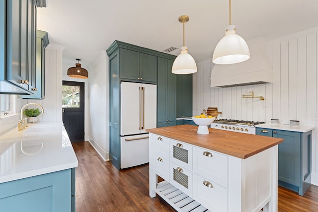 kitchen with a sink, wood counters, high end fridge, a center island, and pendant lighting