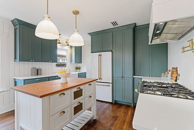 kitchen featuring high end white refrigerator, custom range hood, butcher block countertops, a kitchen island, and pendant lighting