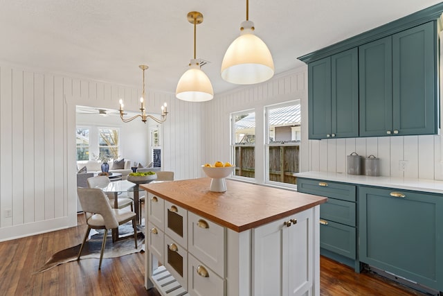 kitchen featuring dark wood-style floors, a center island, butcher block counters, hanging light fixtures, and a chandelier