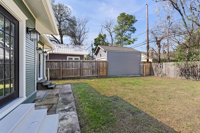 view of yard featuring entry steps, an outbuilding, and a fenced backyard