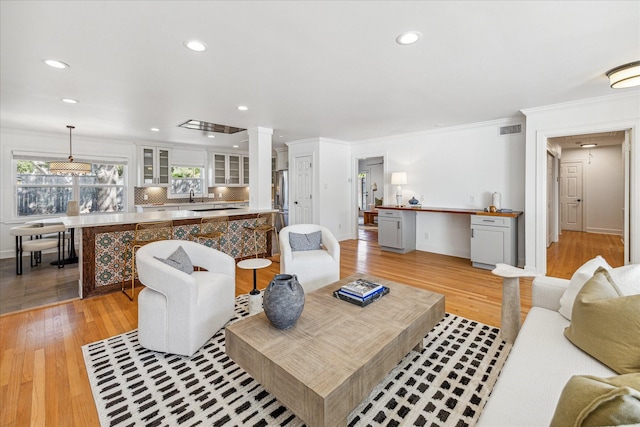 living room featuring decorative columns, visible vents, crown molding, light wood-type flooring, and recessed lighting