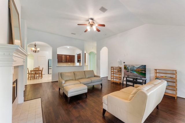 living room featuring visible vents, arched walkways, lofted ceiling, wood finished floors, and ceiling fan with notable chandelier