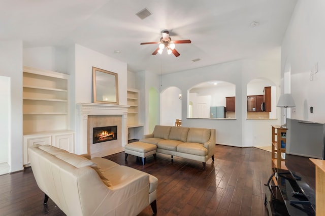 living area with dark wood-style floors, a tile fireplace, visible vents, and ceiling fan