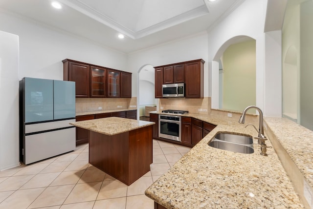 kitchen with light stone countertops, appliances with stainless steel finishes, a sink, and a center island