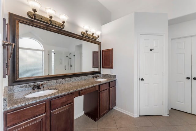 bathroom with a shower stall, double vanity, a sink, and tile patterned floors