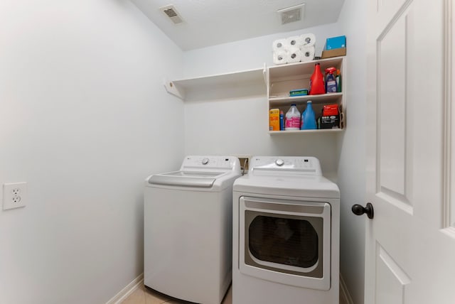 washroom with washing machine and dryer, laundry area, visible vents, and baseboards