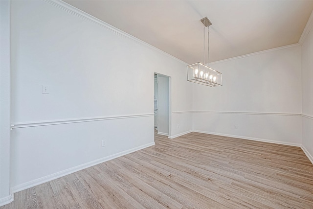 spare room with a notable chandelier, ornamental molding, wood finished floors, and baseboards