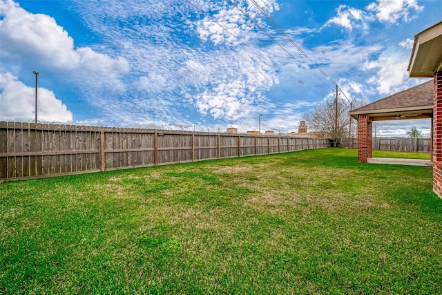 view of yard featuring ceiling fan and a fenced backyard